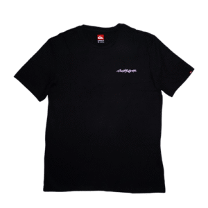👕 Remera negra de corte estándar para hombre marca Quiksilver. Pequeño logo de firma en el pecho y gran estampa en la espalda de un surfista volando sobre una ola en colores uva, amarillo y azul