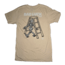 👕 Remera beige ecru de corte estándar para hombre marca Chomp. Pequeño logo de dientes en el pecho y gran estampa de esqueleto caminando bajo escalera con leyenda "BAD LUCK CLUB" en la espalda